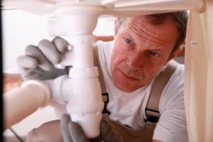 a Lakewood Plumber installs a new drain beneath a kitchen sink